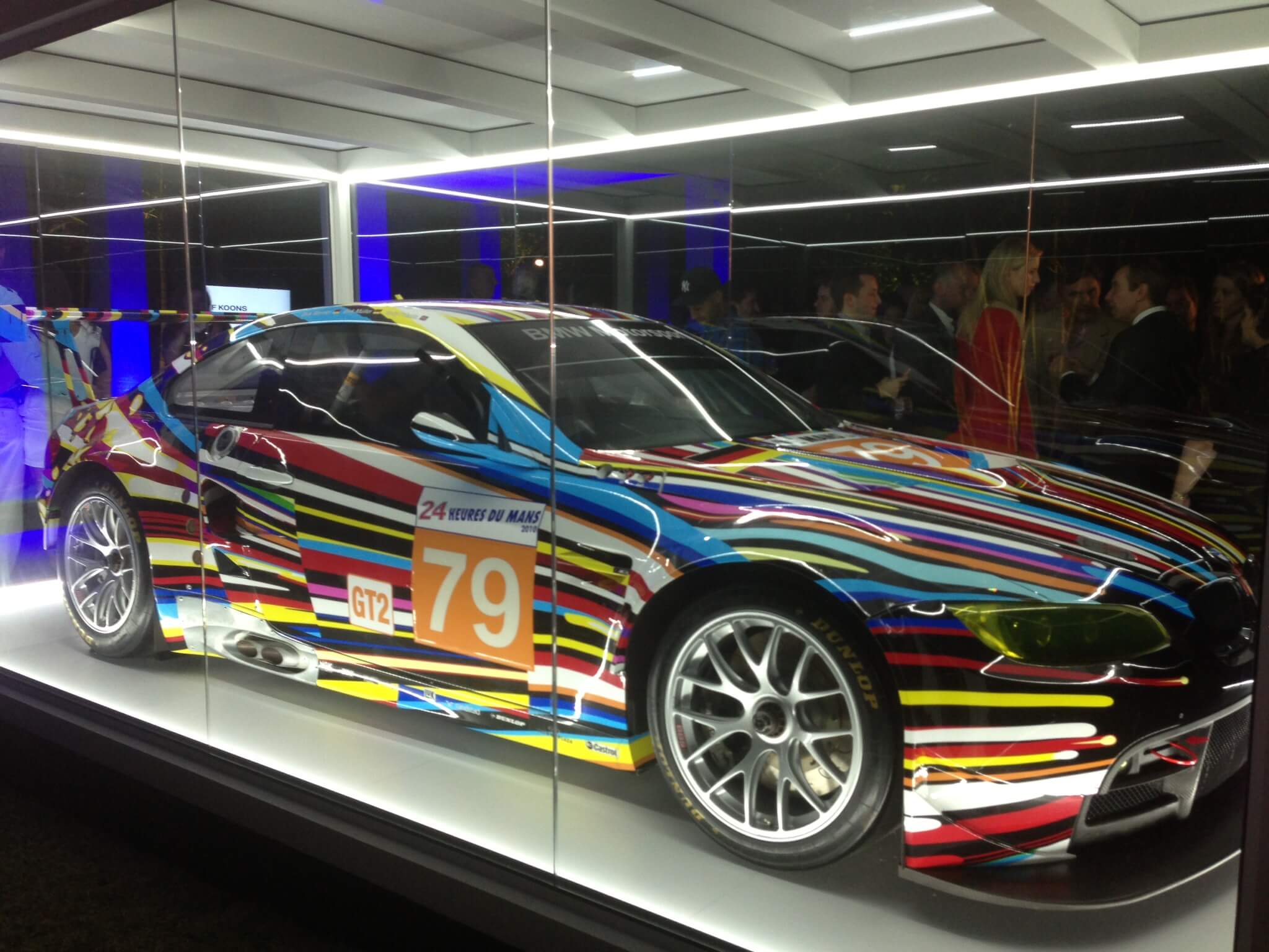 A colorful car on display in a glass case
