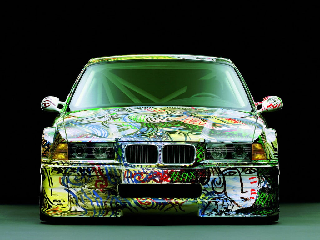 A car covered in graffiti on a black background
