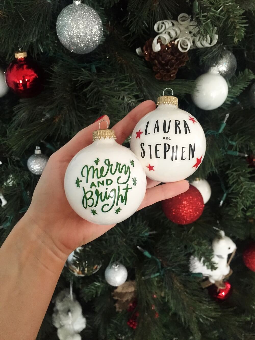 A person holding a christmas ornament in front of a christmas tree
