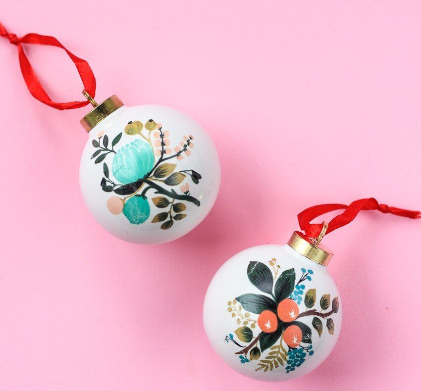 Two white ornaments with a red ribbon on a pink background
