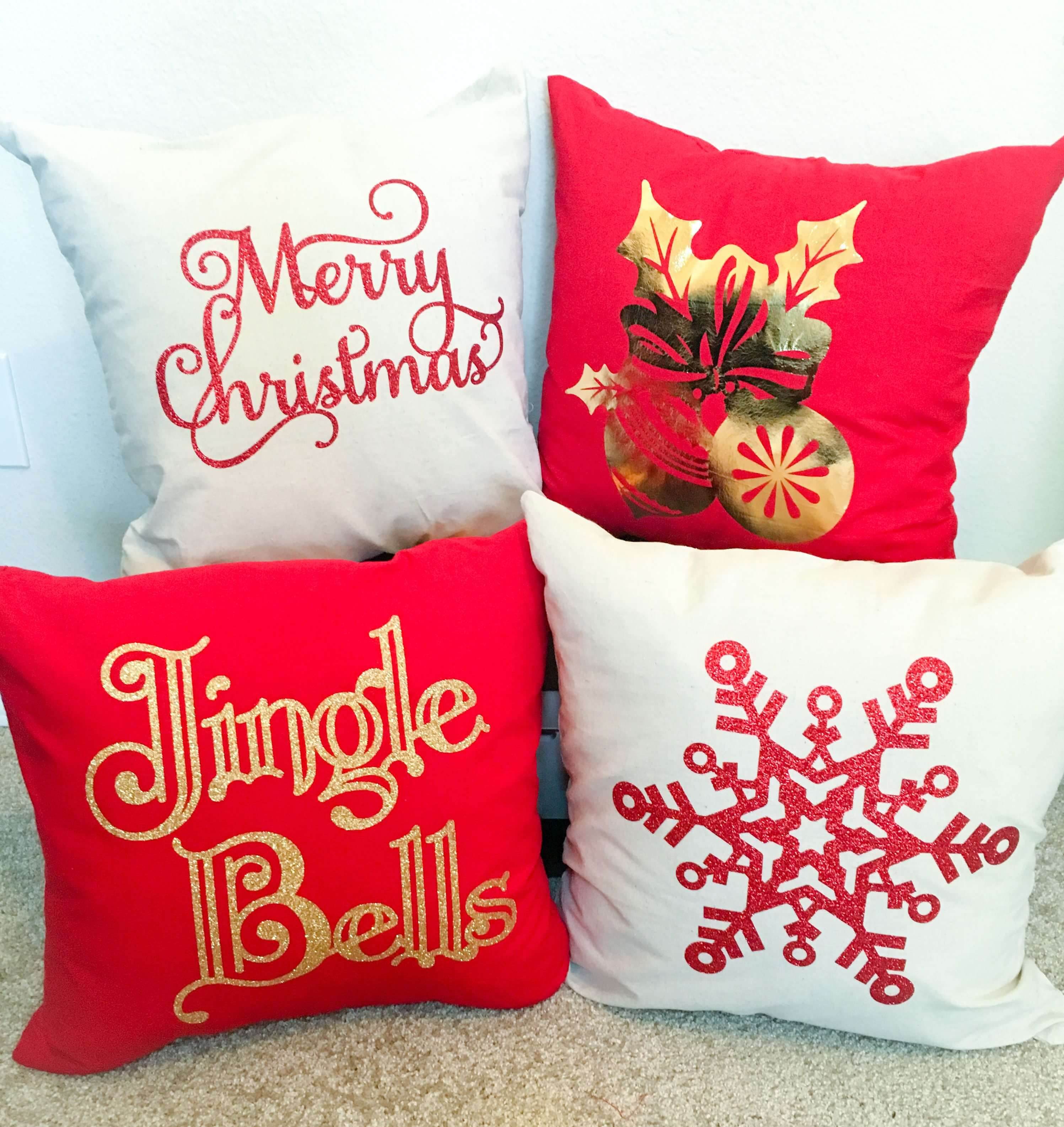 A group of four christmas pillows sitting on top of a floor
