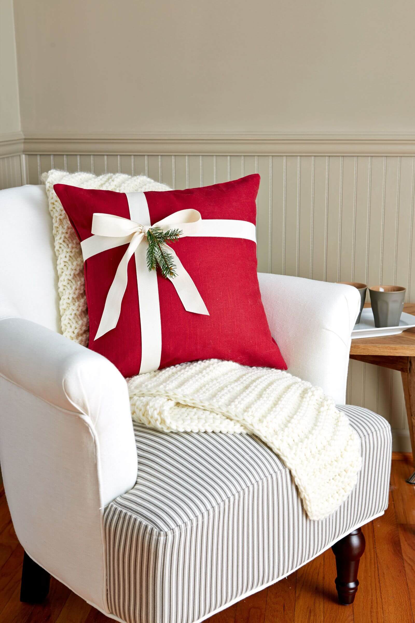 A white chair with a red pillow on it
