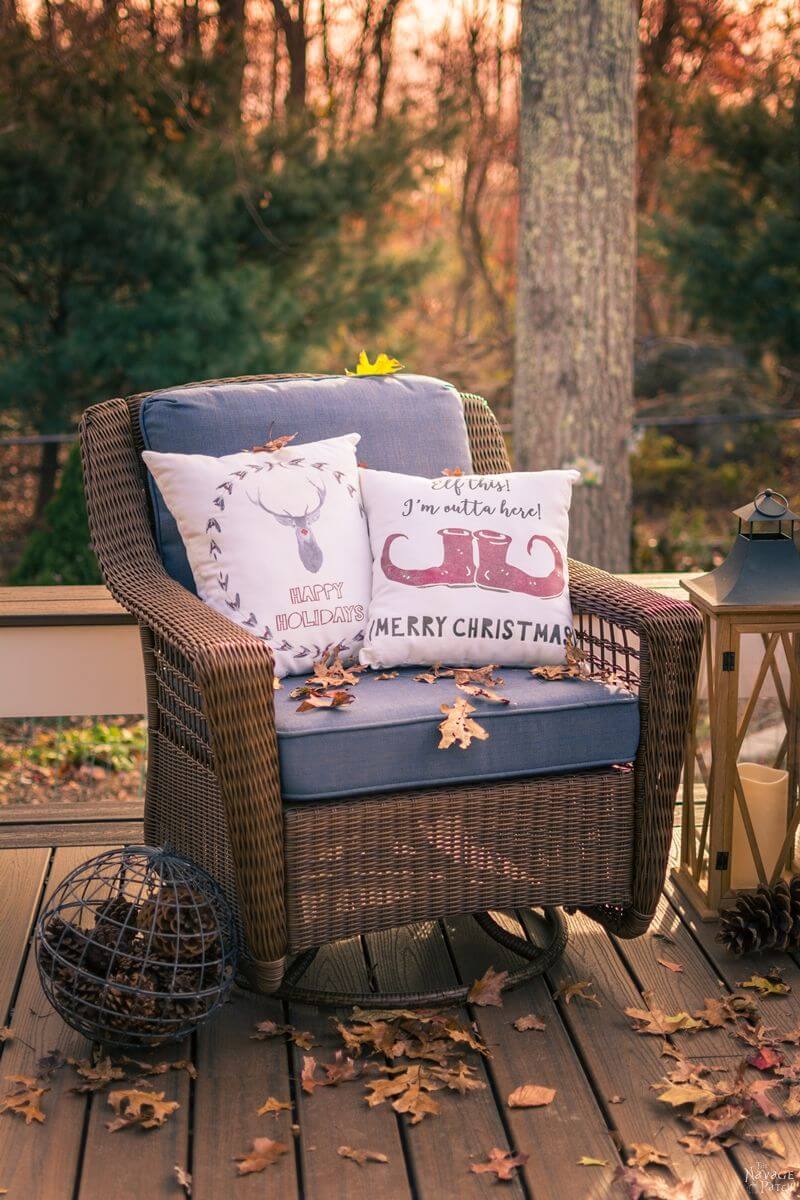 A chair on a deck with pillows and a lantern
