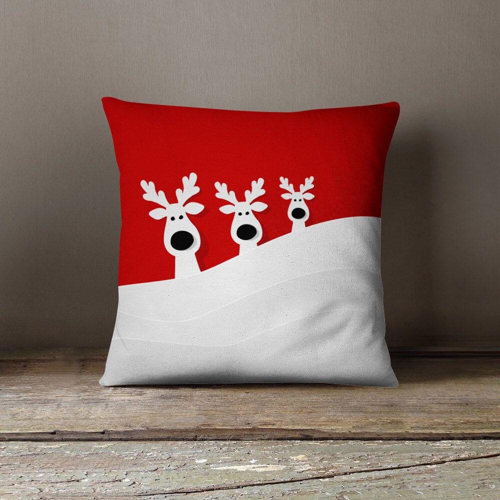 A red and white pillow with two reindeers on it
