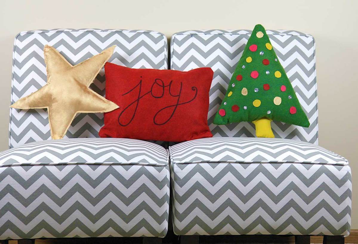A gray and white couch with a christmas tree pillow on it
