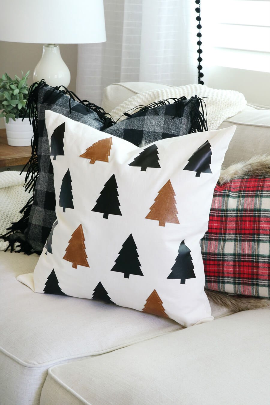 A white couch with a black and white christmas tree pillow on it
