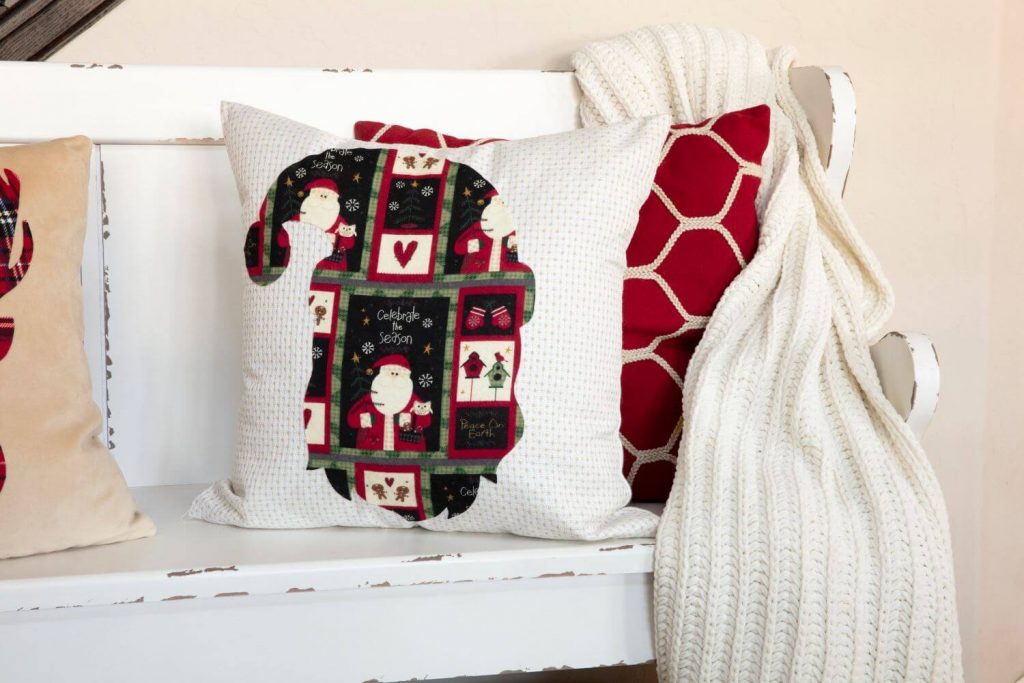 A white bench topped with pillows and a blanket
