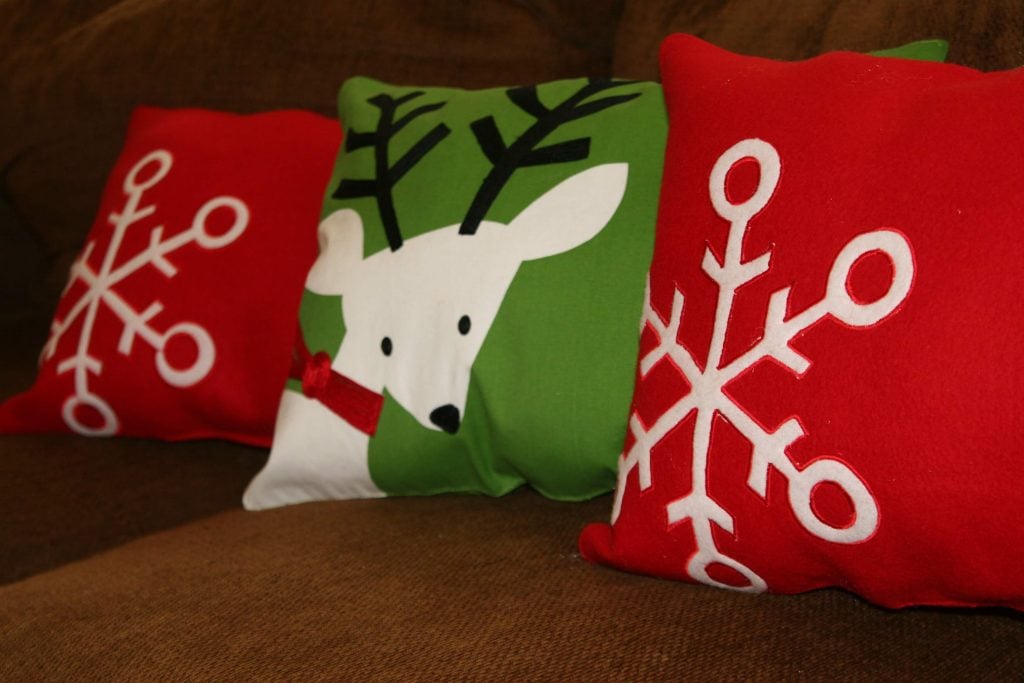 Three red and green christmas pillows on a couch

