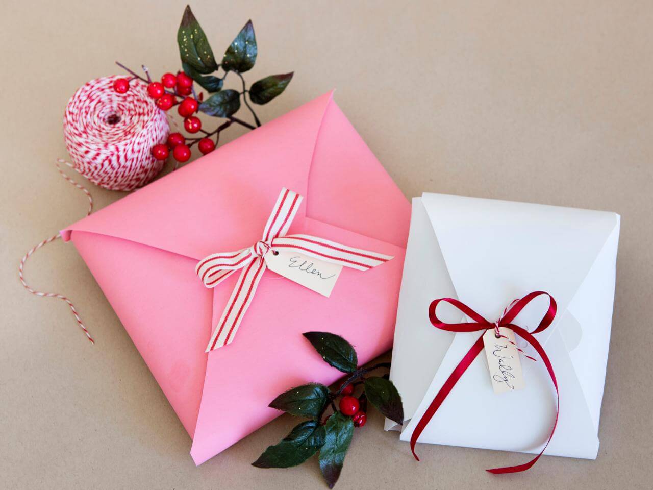 A pink envelope and a white envelope with a red ribbon
