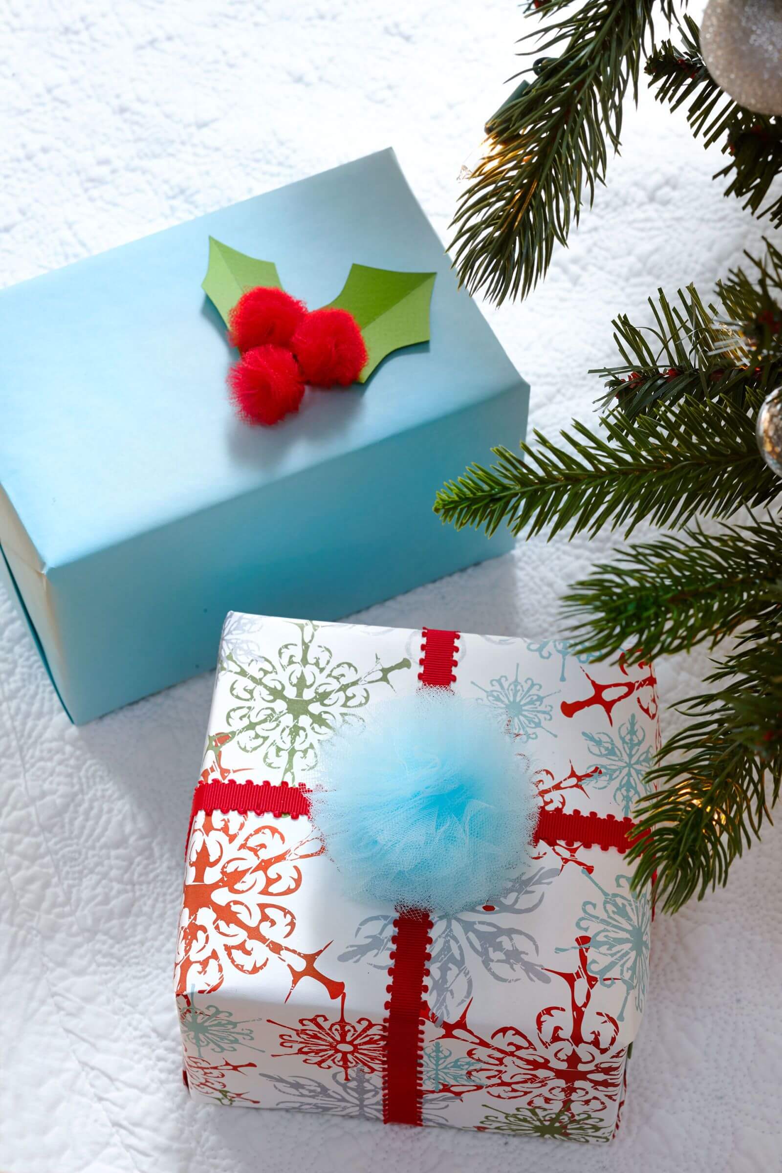 A blue box with a red pom pom on top of it next to
