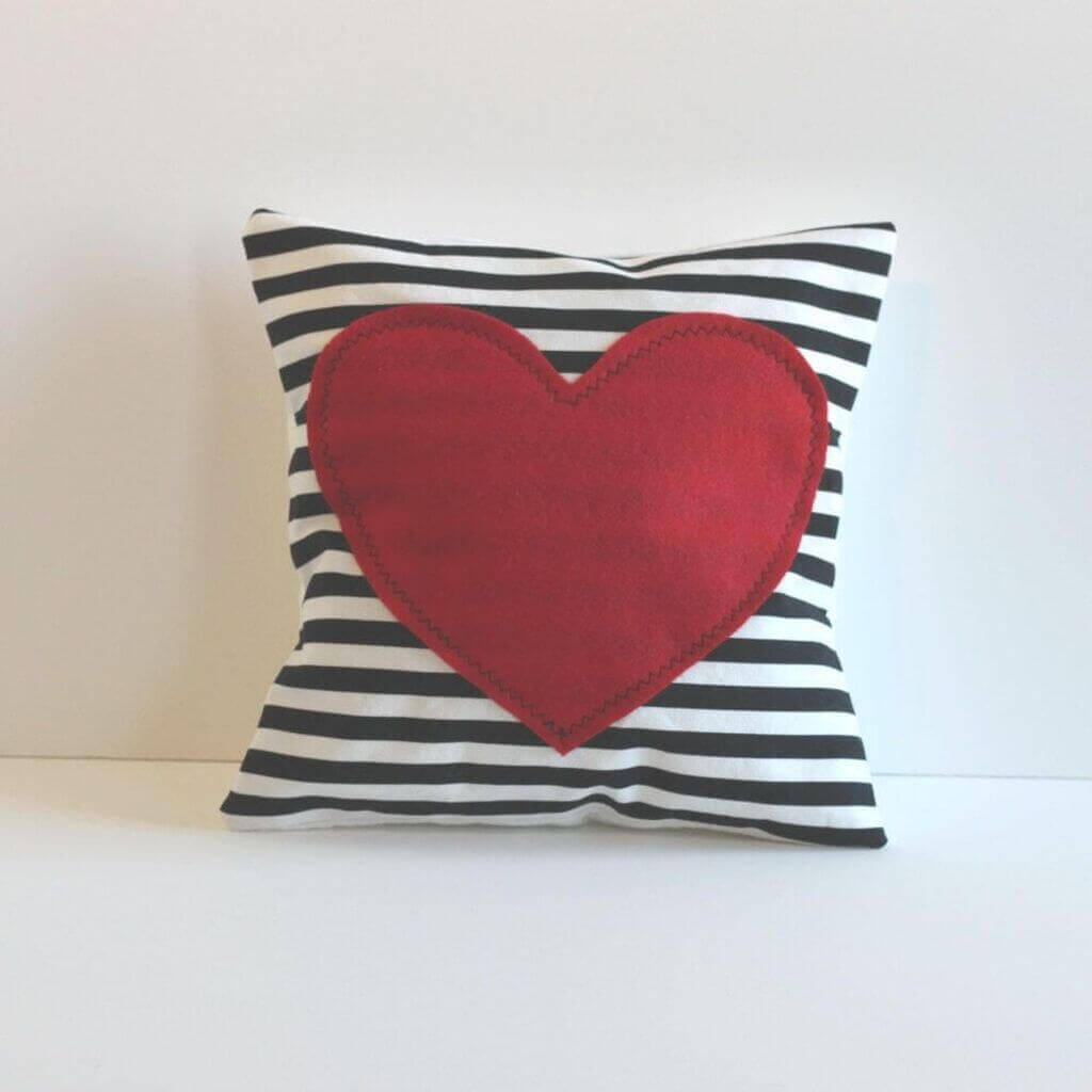 A red heart on a black and white striped pillow
