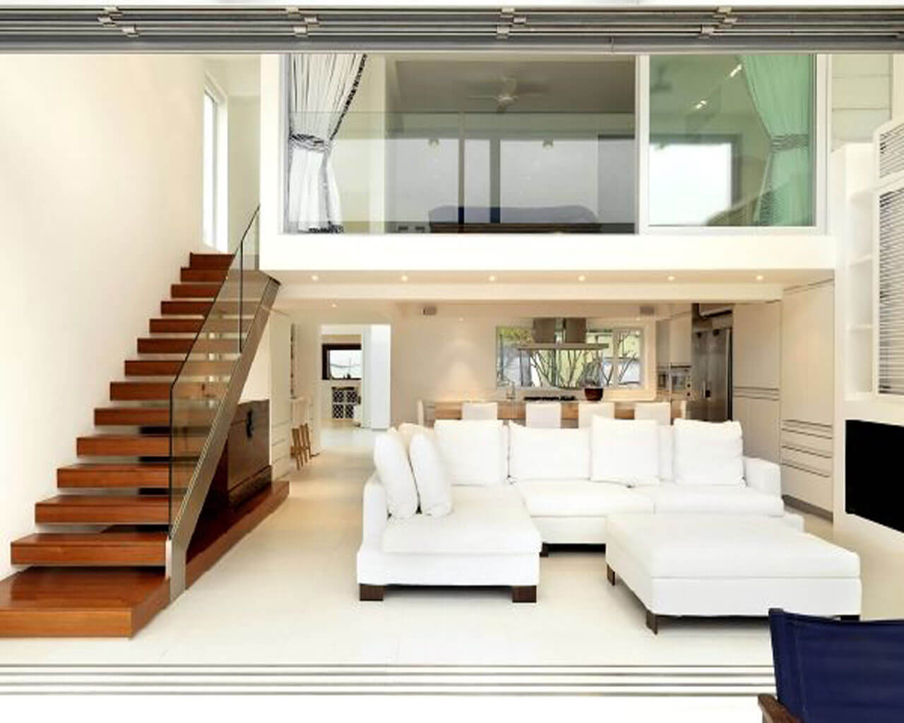 A living room filled with white furniture and a stair case
