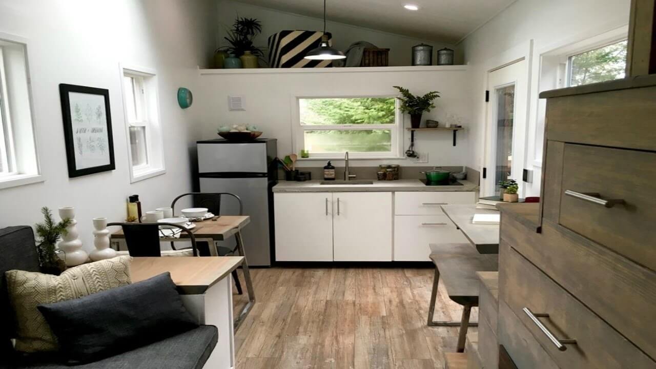 A kitchen with white cabinets and wood floors
