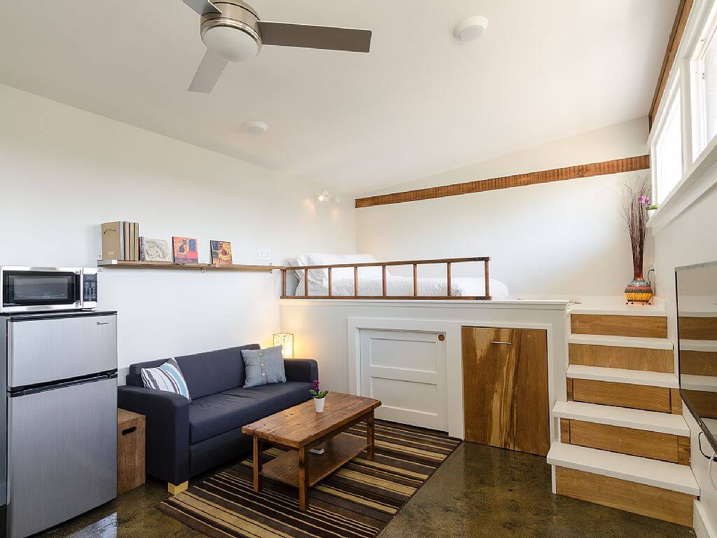 A living room with a couch a table and a refrigerator
