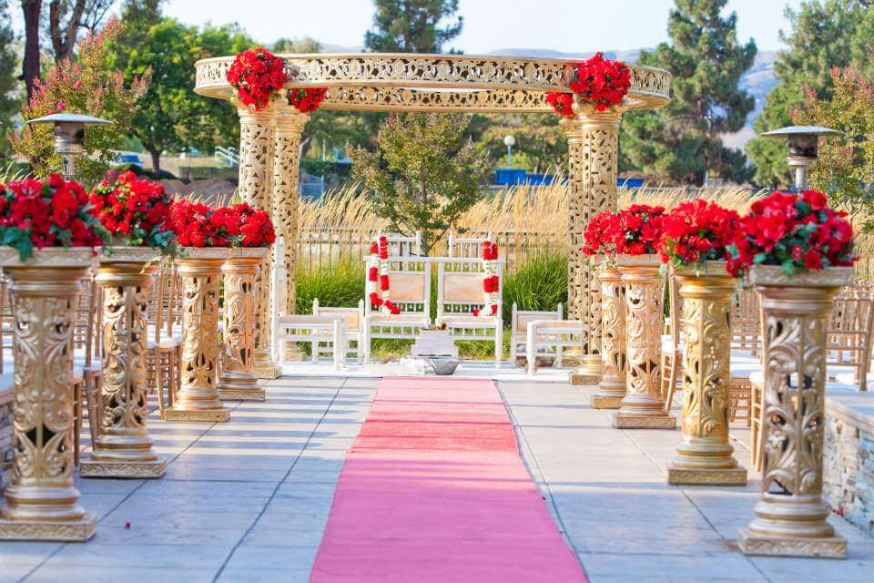 A wedding ceremony with red flowers and white chairs
