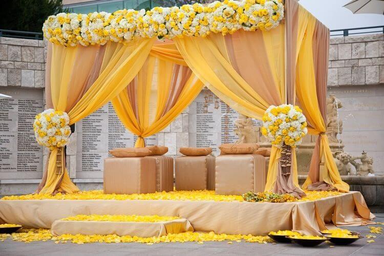 A decorated stage with yellow draping and flowers
