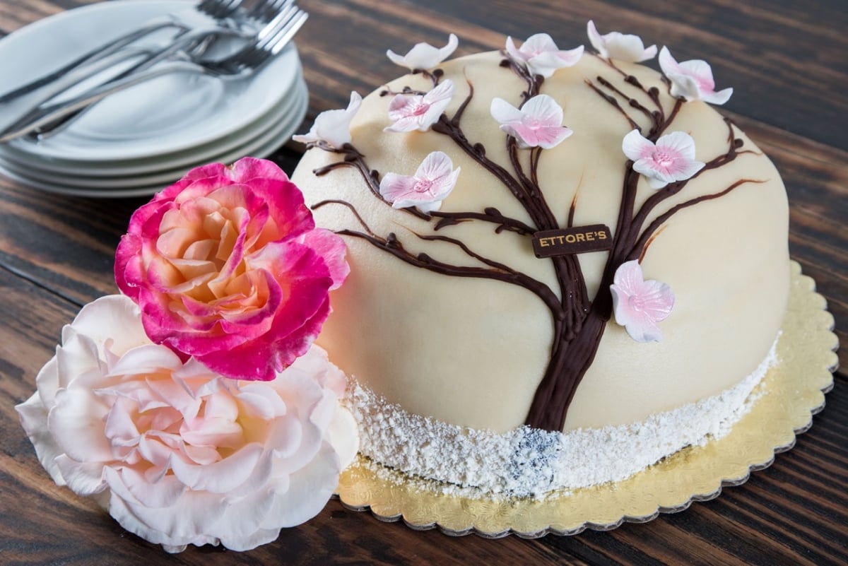 A cake decorated with a tree and flowers on a table
