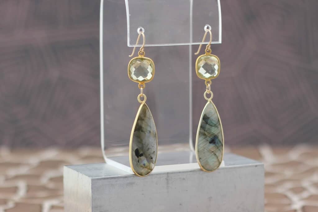 A pair of earrings with a green stone hanging from it
