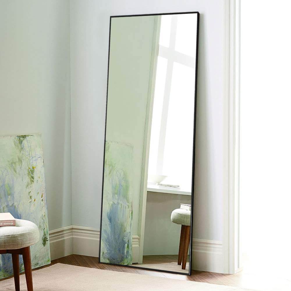 A large mirror sitting on top of a floor next to a chair
