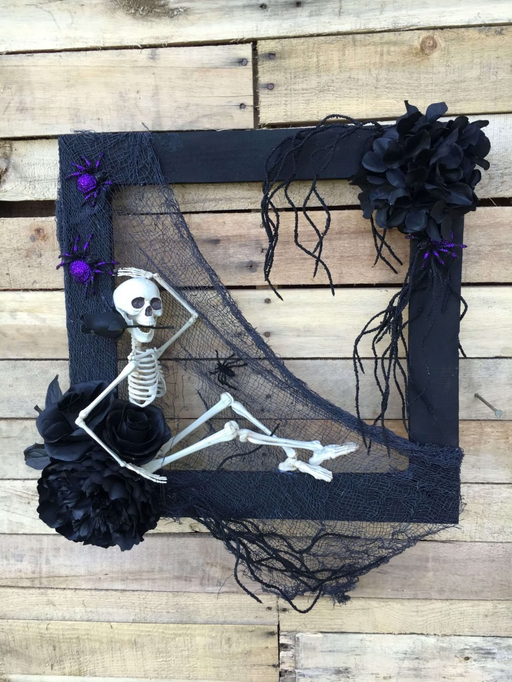 A picture frame with a skeleton and flowers on it
