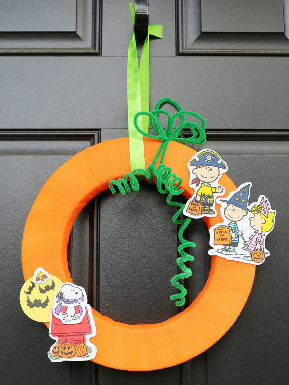 An orange wreath with a green ribbon hanging on a door
