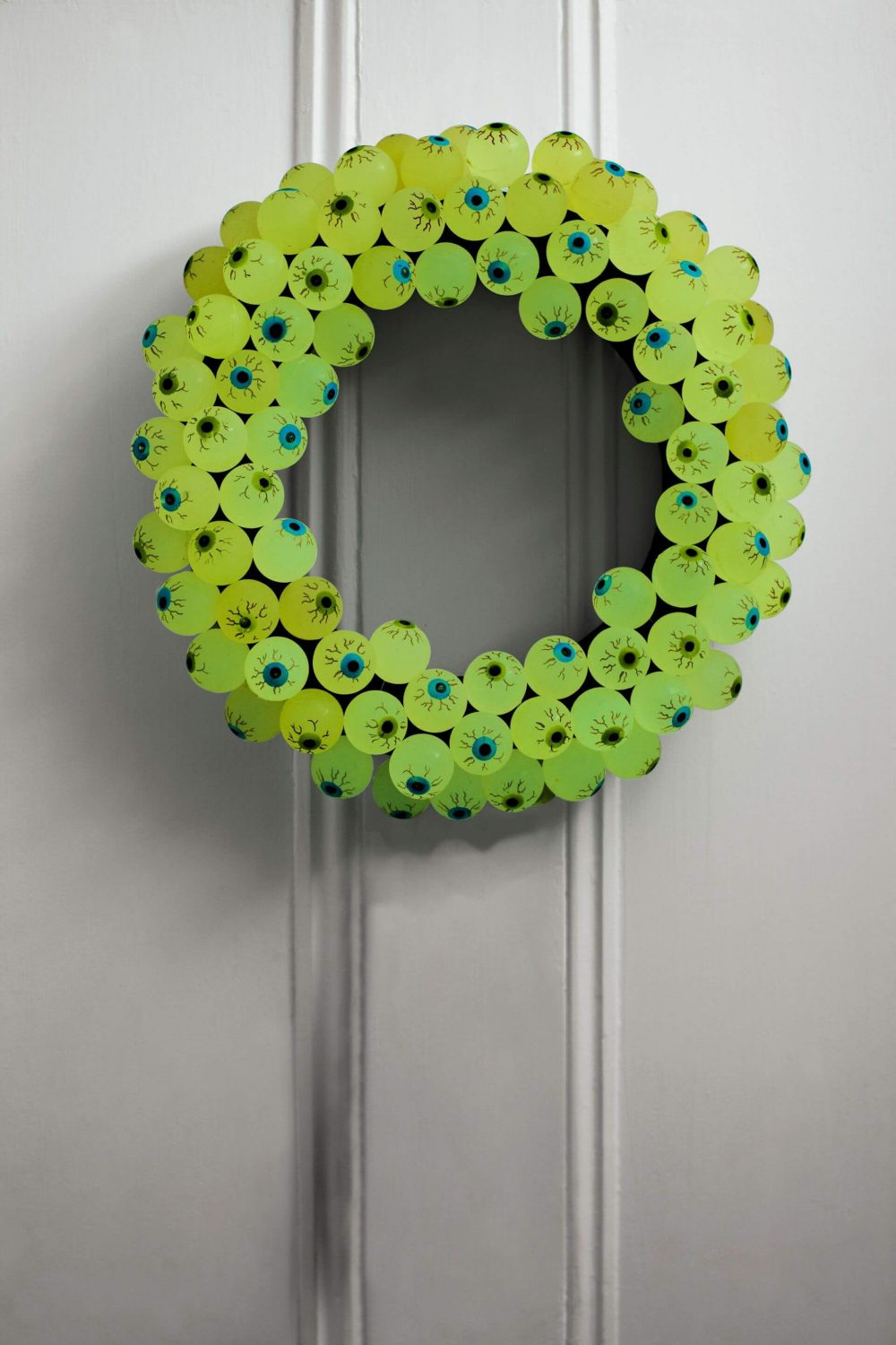 A green wreath hanging on a white door

