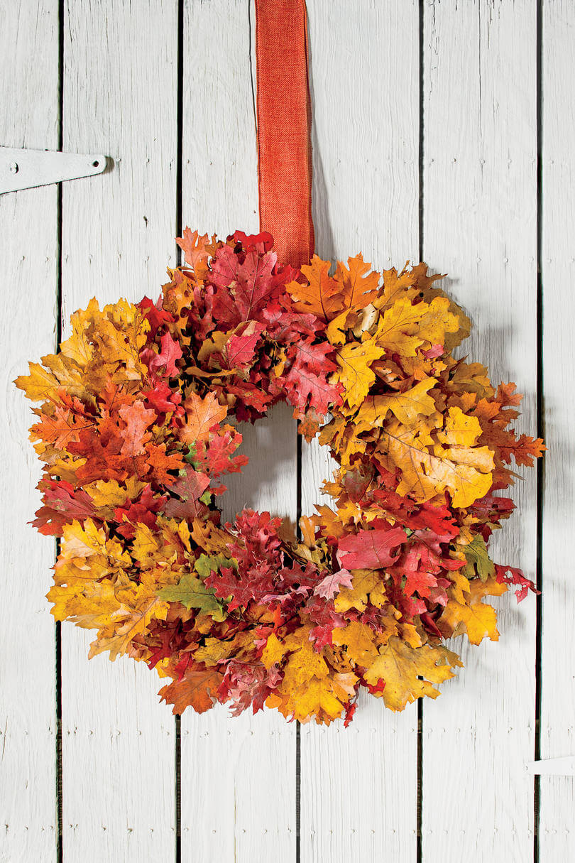 A fall wreath hanging on a white wooden wall
