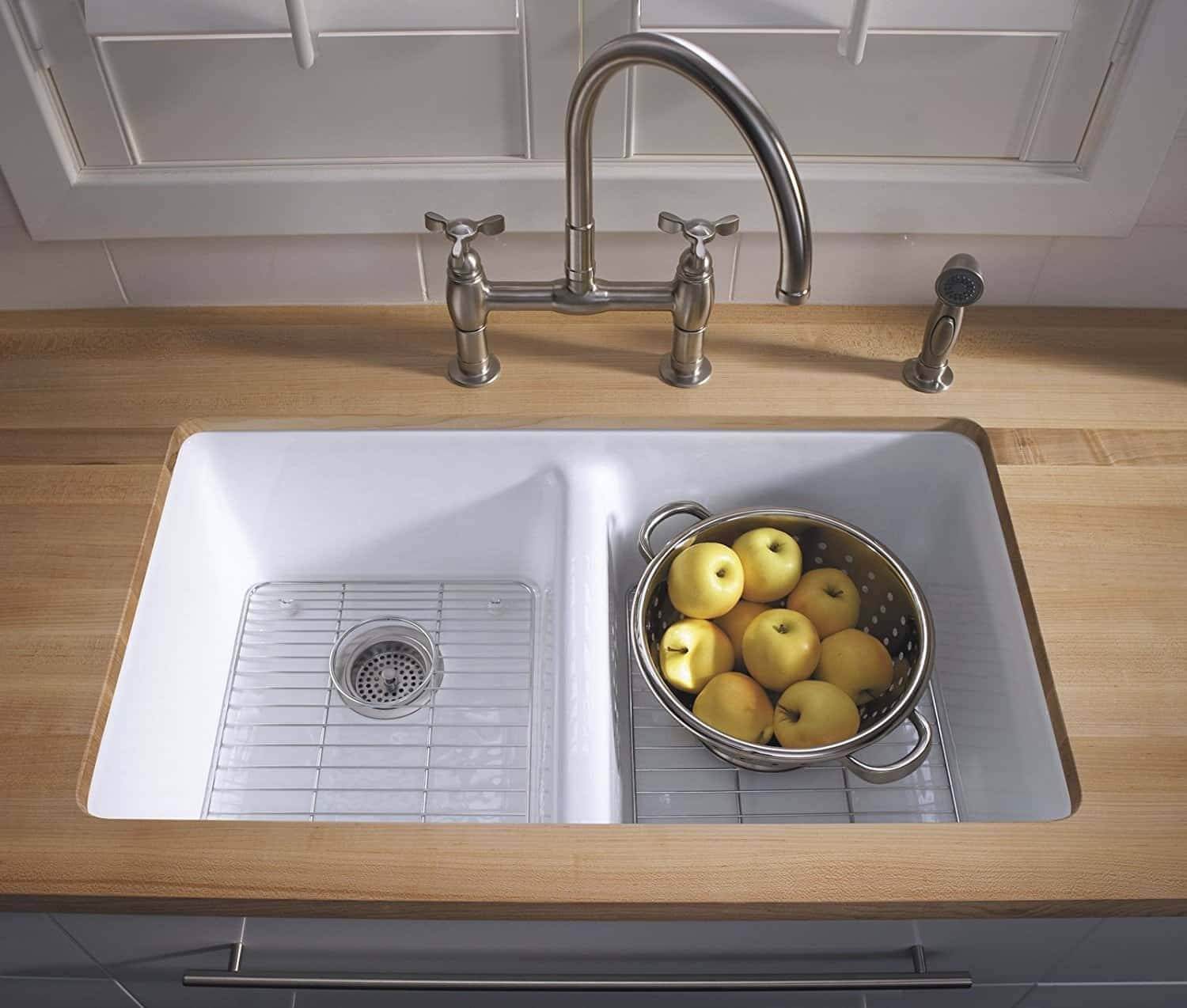 A white kitchen sink with a basket of apples.