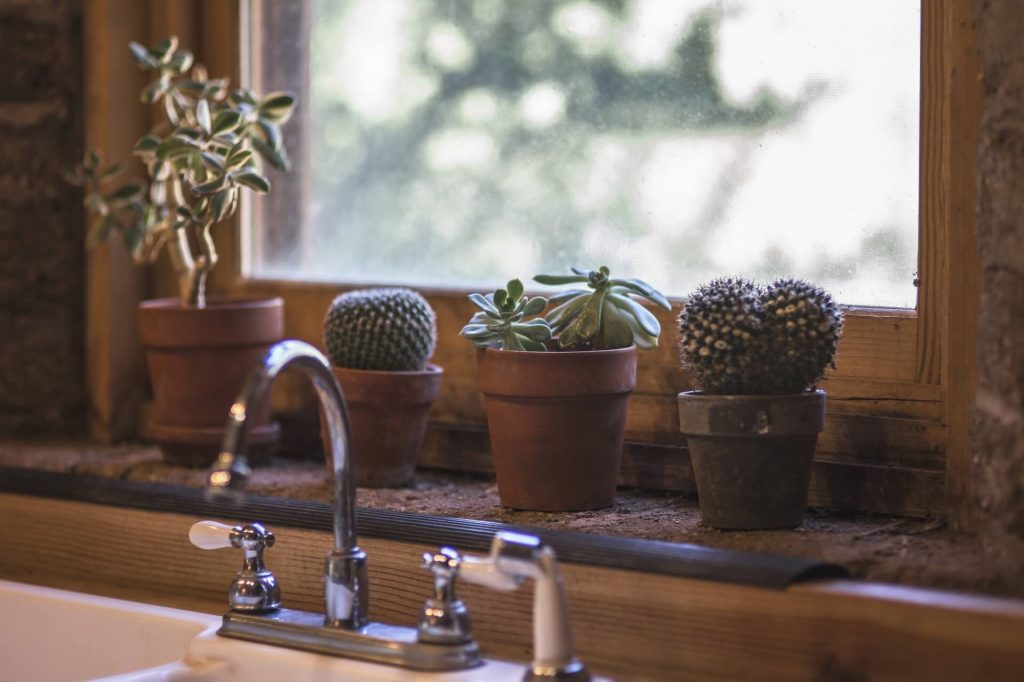 A window sill filled with potted plants next to a sink

