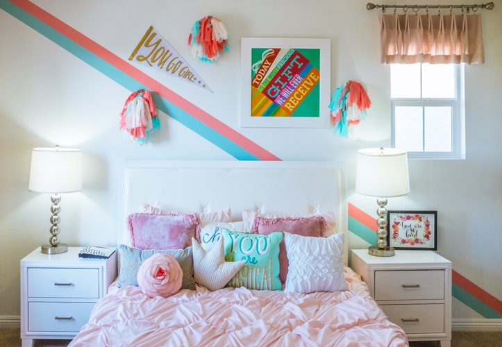 A bedroom with a bed, dresser, and pictures on the wall
