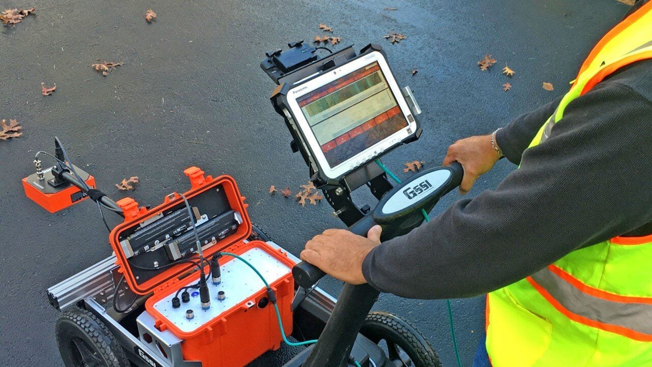 A man in a safety vest is operating a Ground-Penetrating Radar (GPR)
