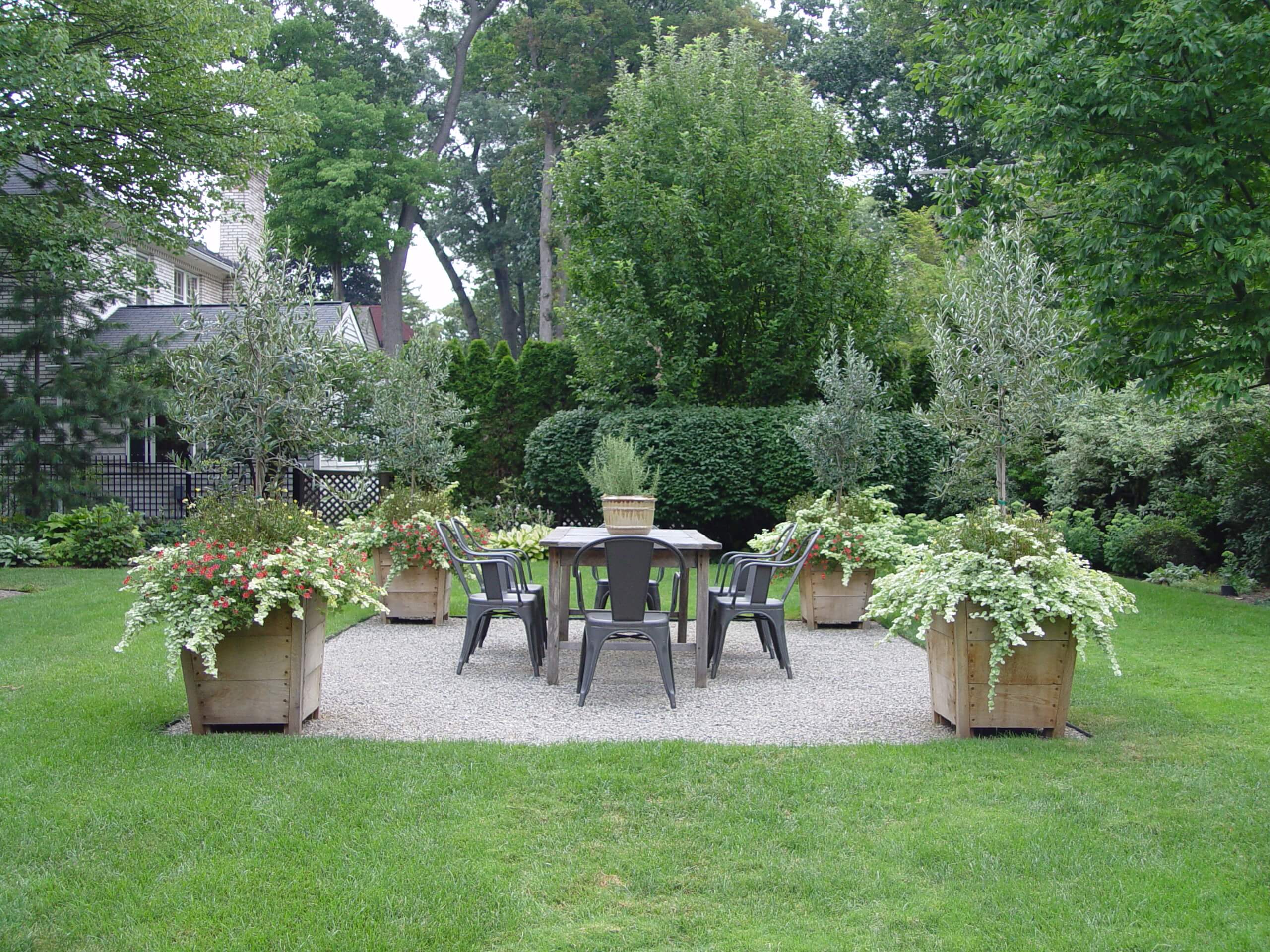 A garden with a table, chairs and potted plants.