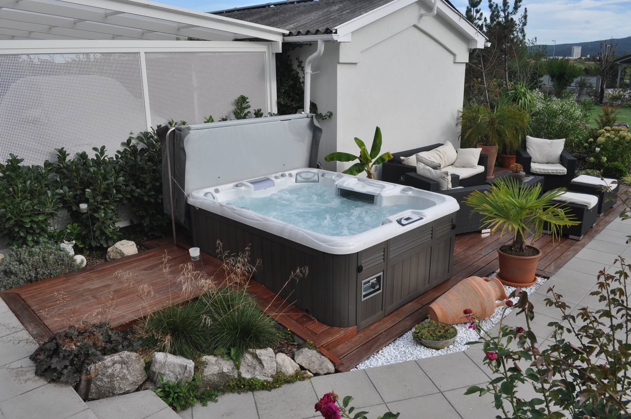 A hot tub on a wooden deck in a backyard.