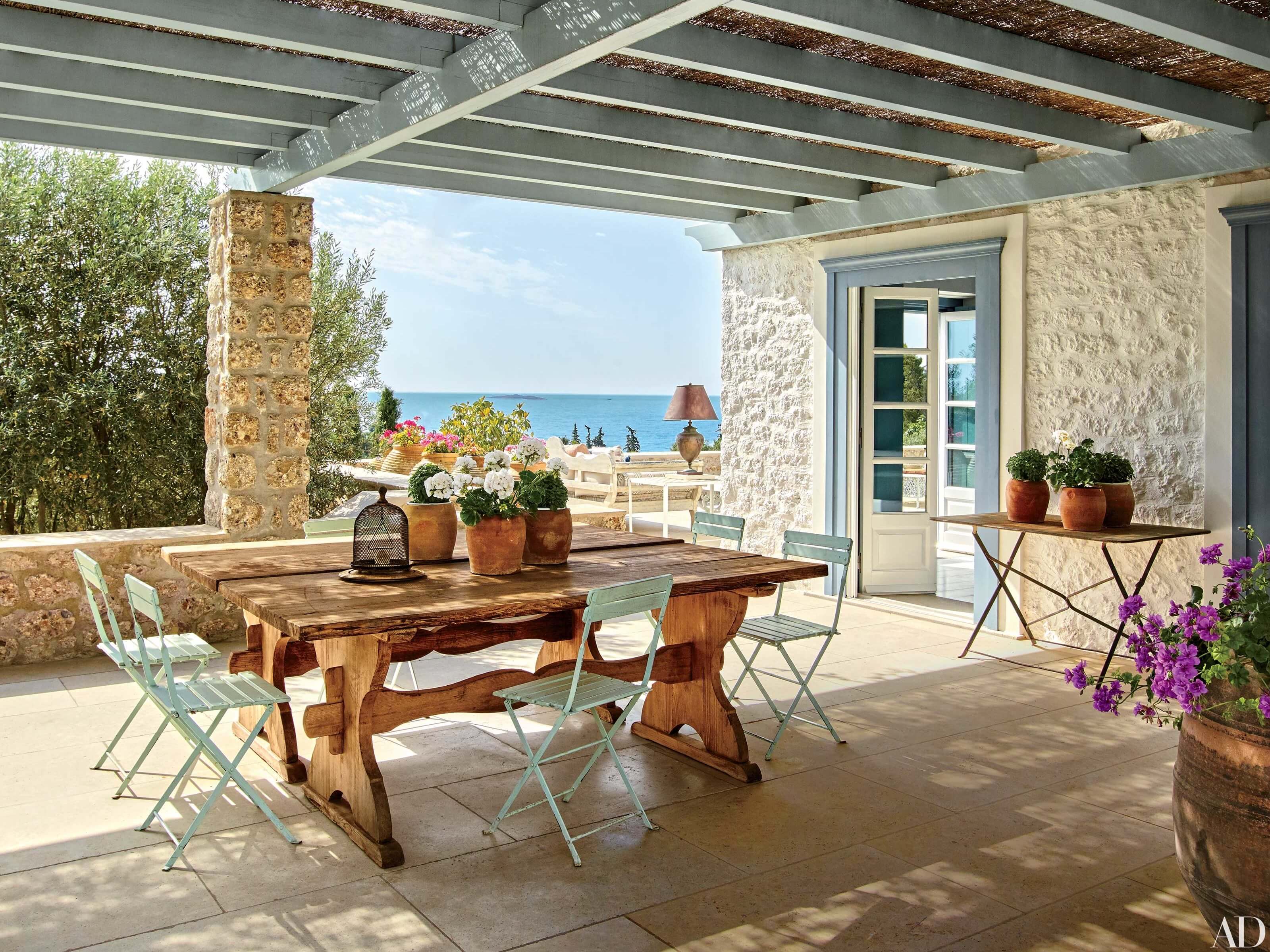 A patio with a table and chairs overlooking the ocean.