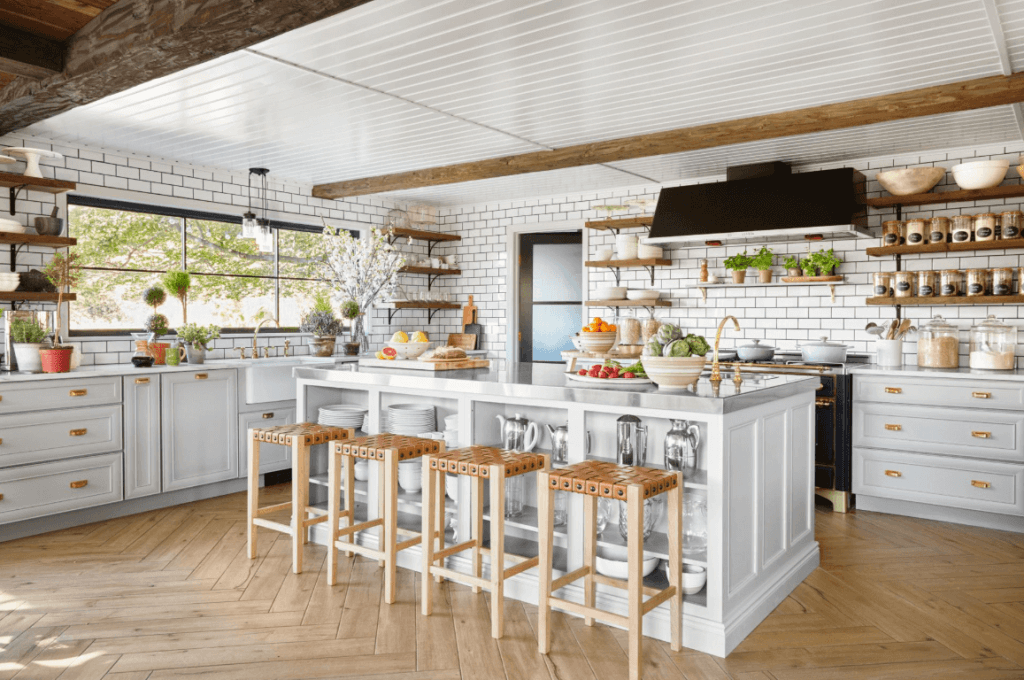 A white kitchen with wooden floors and wooden stools.