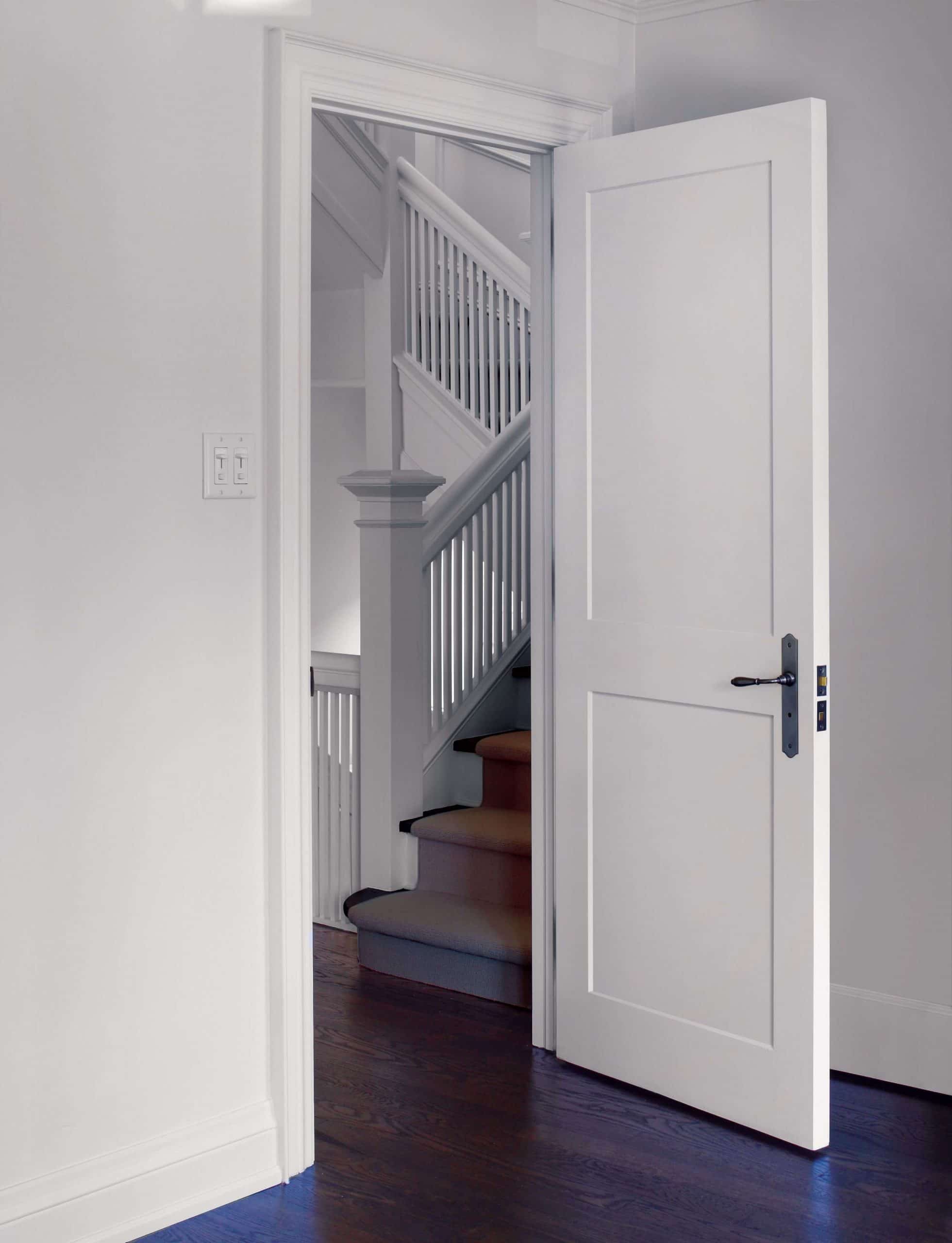 An open panel door leading to a stairway in a house
