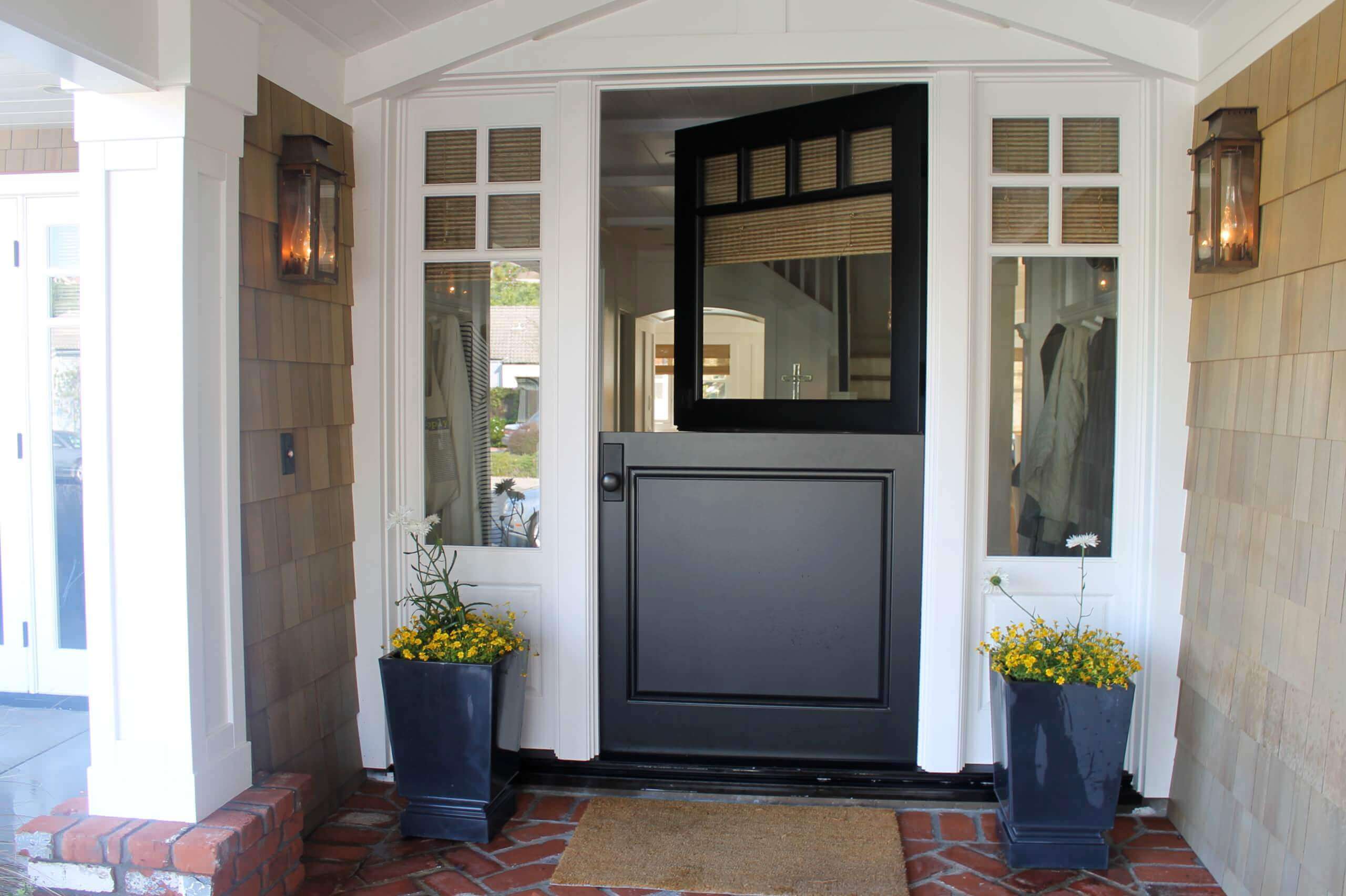 A black front dutch door with two blue planters
