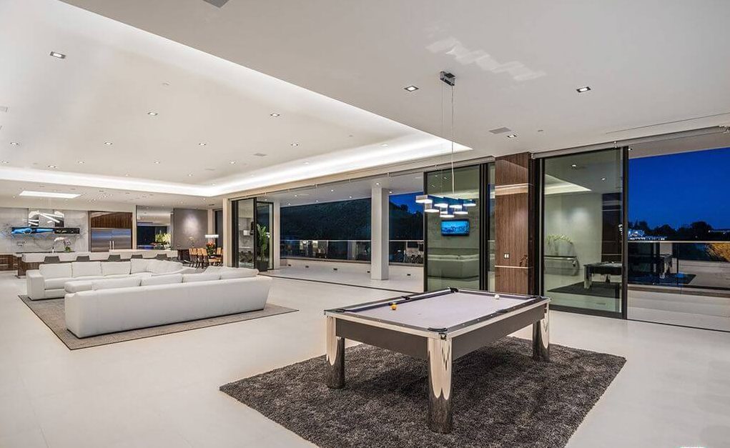 A living room with a pool table and couches
