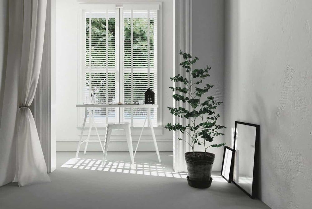 A white room with a potted plant next to a window
