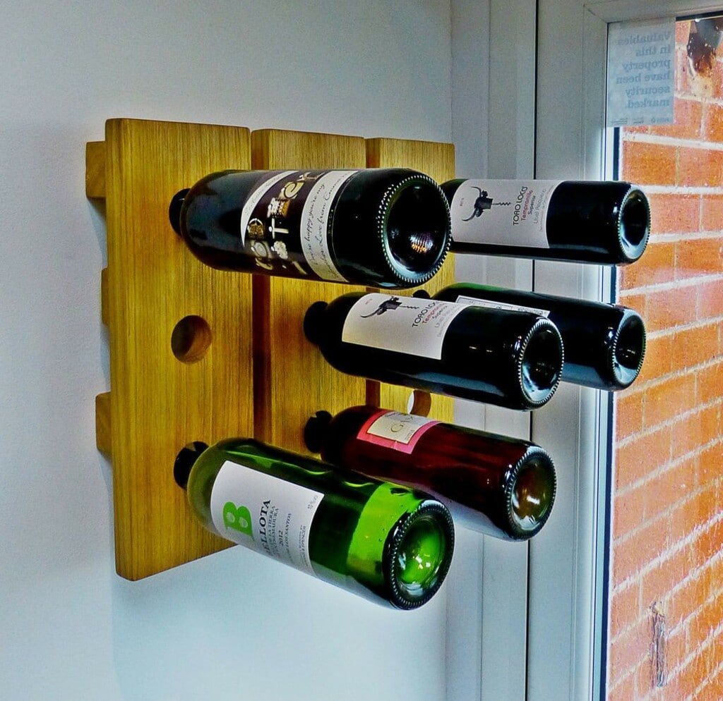 A wall mounted wine rack with three bottles of wine
