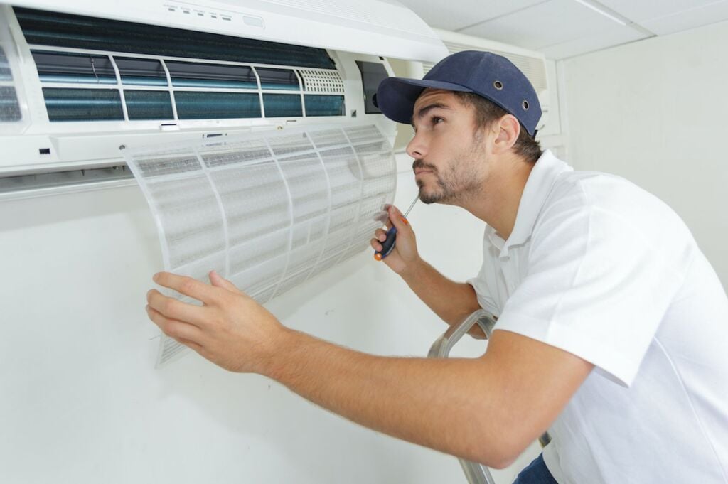 A man working on a window air conditioner
