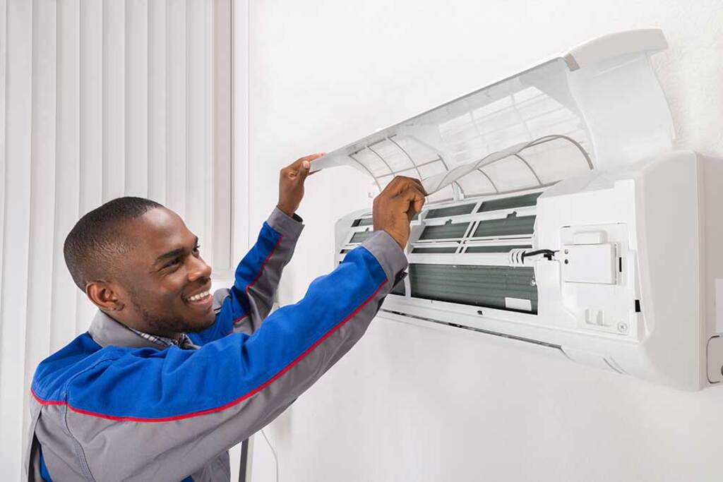 A man adjusting the air conditioner on a wall
