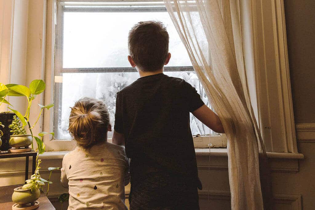 A boy and a girl looking out a window
