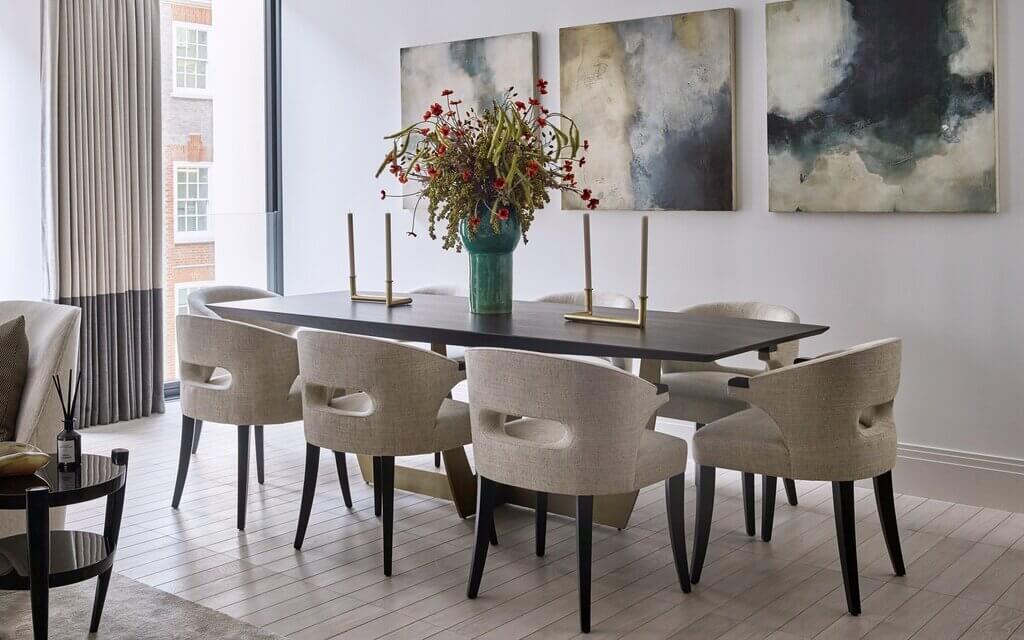 A dining room table with chairs and a vase of flowers
