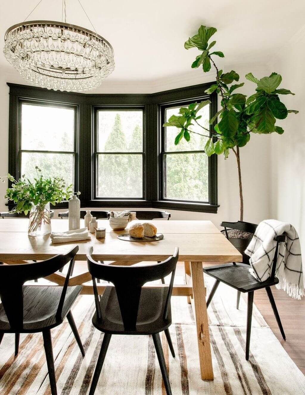 A dining room table with chairs and a potted plant
