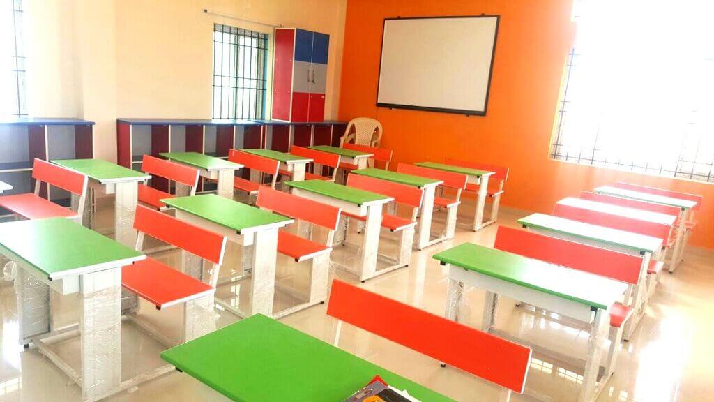 A classroom filled with lots of green and red desks
