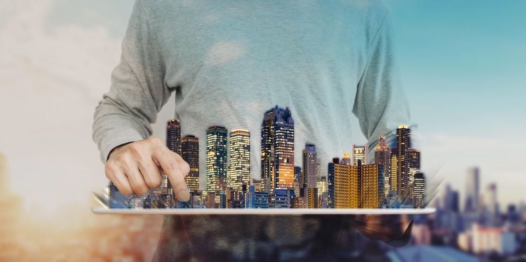 A man holding a tablet with a city in the background

