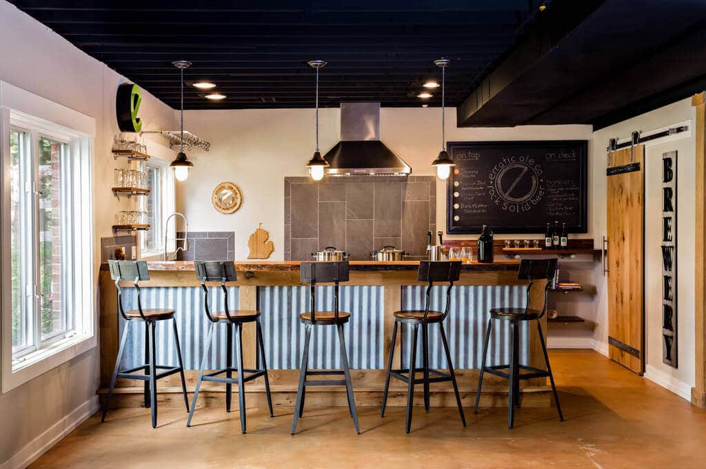 
A kitchen with a bar with mid century bar stools and a chalkboard on the wall
