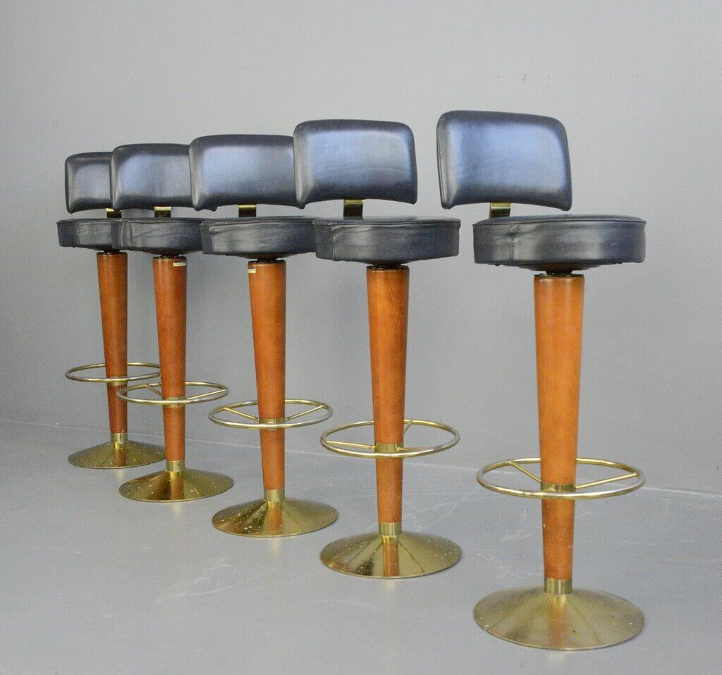 A set of four mid century modern bar stools with wooden legs
