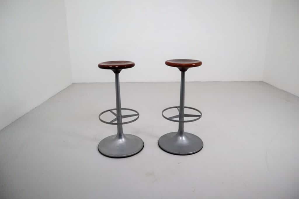 A couple of mid century modern bar stools sitting on top of a white floor
